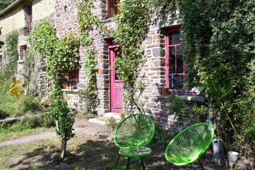 duas cadeiras verdes sentadas em frente a um edifício em La Maison des Hirondelles Forêt de Brocéciande em Saint-Malon-sur-Mel