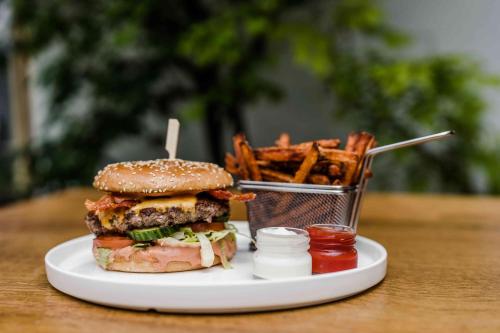 a plate with a hamburger and a basket of fries at Hotel Antoniushof in Ruhstorf