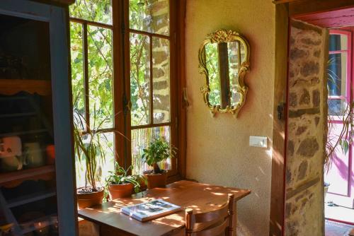 Cette chambre dispose d'une table et d'une fenêtre ornée de plantes. dans l'établissement La Maison des Hirondelles Forêt de Brocéciande, à Saint-Malon-sur-Mel