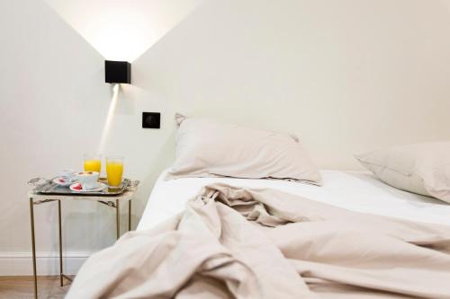 a white bedroom with a bed and a side table at Auberge des braconniers in Ampus