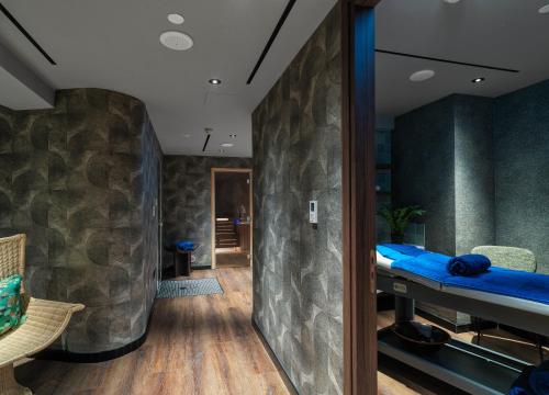 a room with a stone wall and a blue bed at NYX Hotel Limassol in Limassol