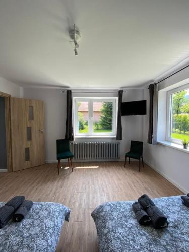 a bedroom with two beds and two windows at Pokoje Green House in Ustroń