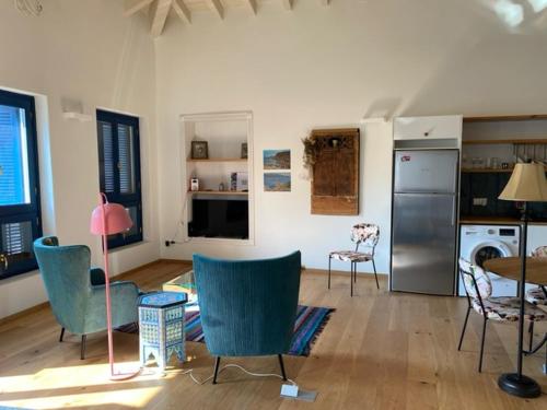 a living room with chairs and a table and a refrigerator at Studio in the Aegean in Meyisti