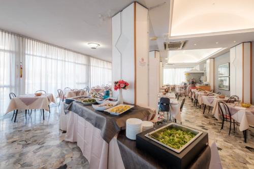 un restaurante con mesas y sillas blancas y un buffet en Hotel Crown, en Rímini