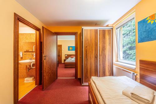 a bedroom with a bed and a bathroom with a sink at Hotel Sluníčko in Ostravice