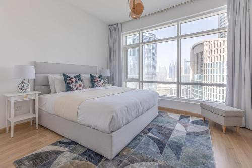 a white bedroom with a bed and a large window at Frank Porter - The Lofts East in Dubai