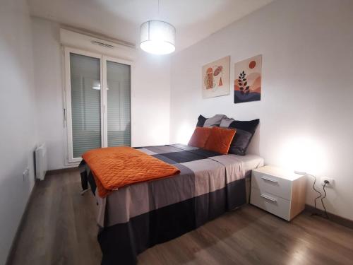 a bedroom with a bed with an orange blanket on it at Appartement Jelyad Mallard proche Disney in Chanteloup-en-Brie