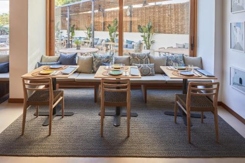 a dining room with a table and chairs and a couch at Hotel Tres Torres in Santa Eularia des Riu