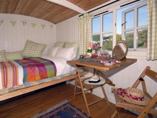 1 dormitorio con 1 cama, escritorio y ventanas en Shepherd's Hut, en Bridgend