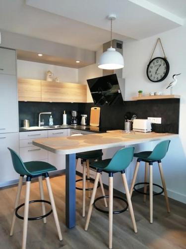 une cuisine avec une table avec quatre chaises et une horloge dans l'établissement appartement Plein Sud, à Auray
