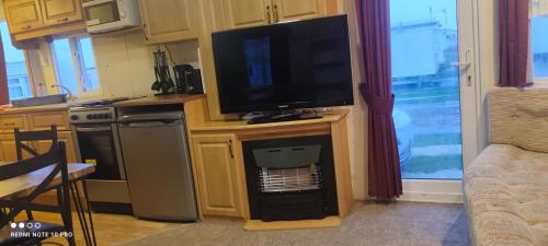 a kitchen with a television on a stand with a table at Beachside, Family-friendly, WiFi, 6 berth Caravans in Ingoldmells