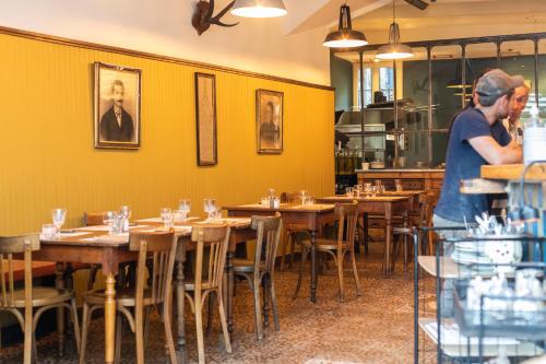 a man standing in a dining room with tables at Auberge des braconniers in Ampus