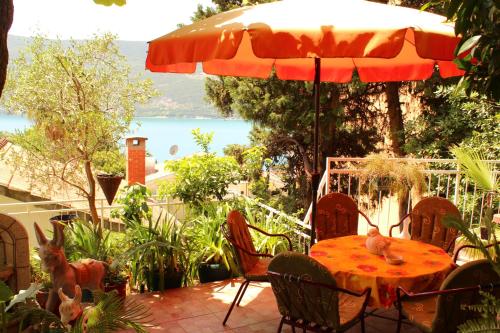 a table and chairs with an umbrella on a patio at Guest House Tomanovic in Herceg-Novi