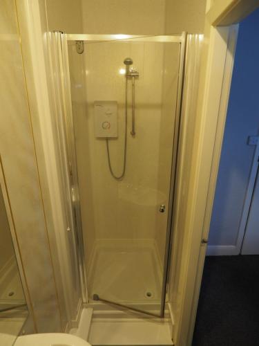 a shower with a glass door next to a toilet at Richmond House in Southport