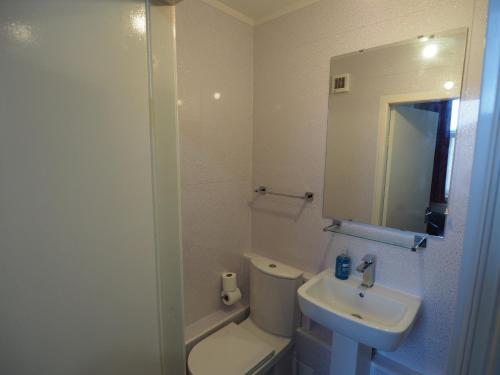 a bathroom with a toilet and a sink and a mirror at Richmond House in Southport