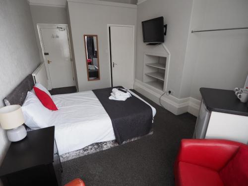 une chambre d'hôtel avec un lit et un fauteuil rouge dans l'établissement Richmond House, à Southport