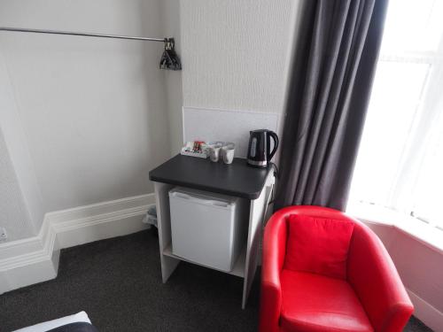 a red chair sitting next to a desk and a window at Richmond House in Southport