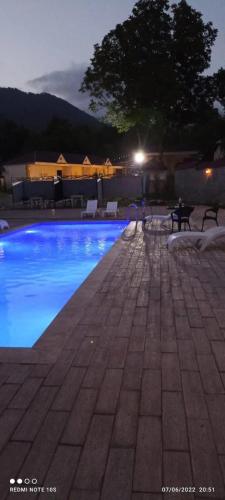 a swimming pool at night with a table and benches at Hamzalli Garden in Gabala
