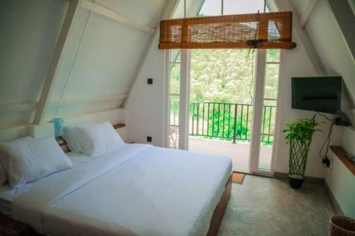Un dormitorio con una gran cama blanca y una ventana en Queenmary cottages, en Nanu Oya