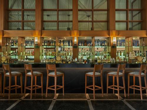 a bar with wooden stools and bottles of alcohol at Angsana Oasis Spa & Resort in Yelahanka