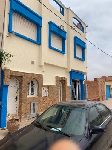 a car parked in front of a building with blue windows at Europa mirlef t aventur Guest House in Mirleft