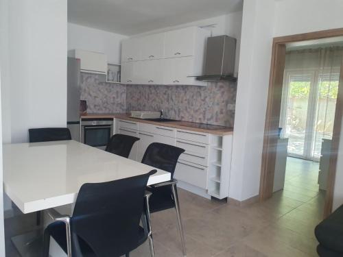 uma cozinha com uma mesa branca e cadeiras pretas em Apartman Amal em Povljana
