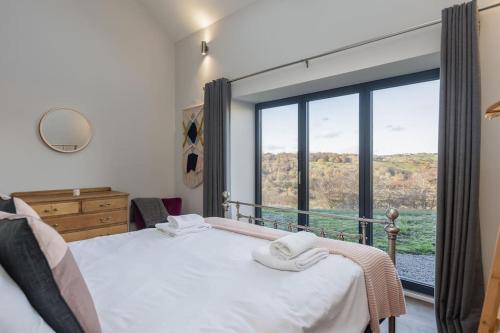 a bedroom with a bed and a large window at Green End Farm Cottages The Stables in Goathland