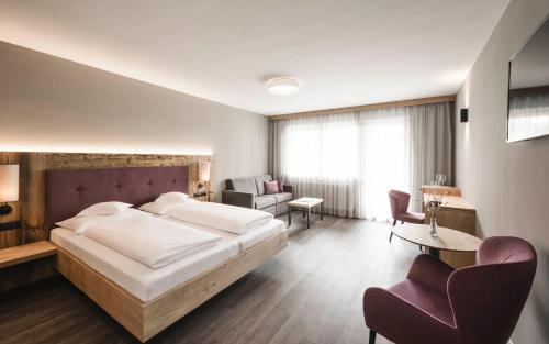 - une chambre avec un grand lit et un salon dans l'établissement Familienhotel Viktoria, à Ultimo