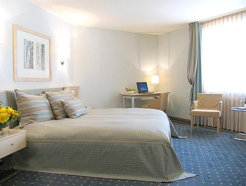 a bedroom with a bed and a desk with a laptop at City Hotel in Schopfheim