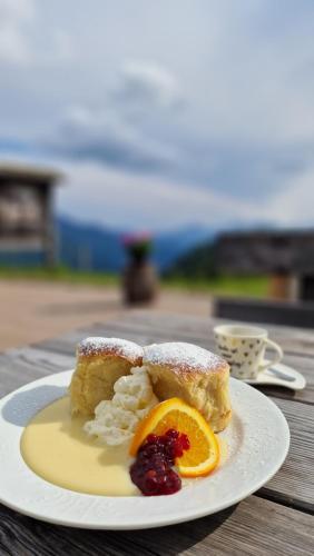 einen Teller mit einem Stück Kuchen und einem Orangenschnitt in der Unterkunft Almgasthaus Glocknerblick in Großkirchheim