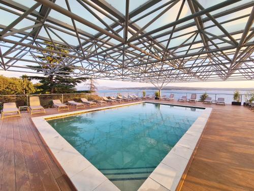 a large swimming pool with chairs and a roof at Hotel Omorika in Crikvenica