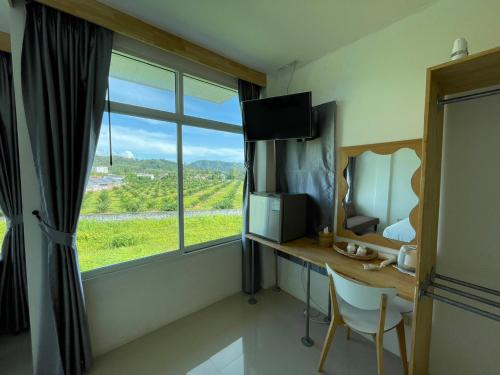 a room with a desk and a window with a view at Dwell Phuket Airport Hotel at Naiyang in Nai Yang Beach
