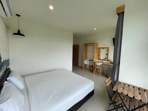 a bedroom with a white bed and a table at Dwell Phuket Airport Hotel at Naiyang in Nai Yang Beach