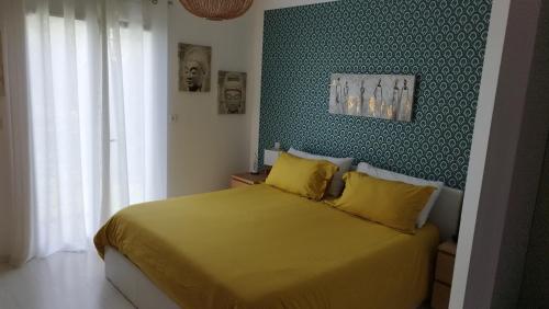 een slaapkamer met een geel bed en een groene muur bij Maison contemporaine à Artigues-près-Bordeaux in Artigues-près-Bordeaux