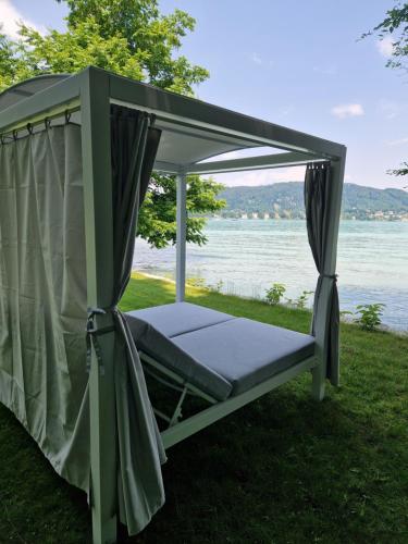 a bed in a gazebo next to the water at Cosy Lake cottage, 300m2 lake area just for you ! in Maria Wörth