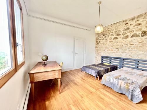 a bedroom with a bed and a desk and window at Les hauts de tison ~ Vue sur la vallée du Clain in Poitiers