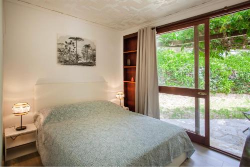 a bedroom with a bed and a large window at U Prato - Bungalow proche de la mer in Lumio