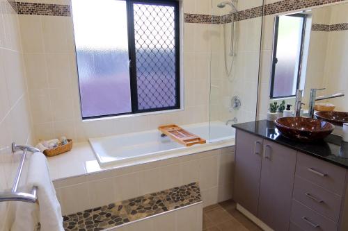 a bathroom with a tub and a sink and a shower at Top End Getaway - Luxury Home in Palmerston