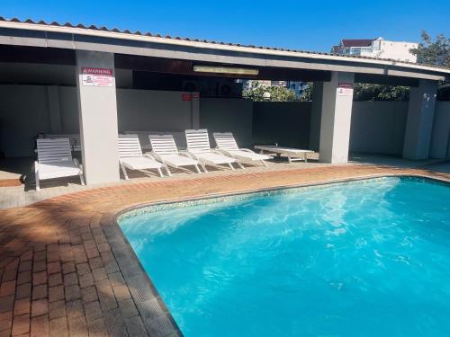 a large swimming pool with chairs and a patio at Santana 804 Beachfront Apartment with spectacular sea views in Margate