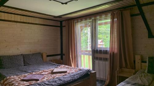 a bedroom with a bed and a large window at 7+я in Verkhovyna