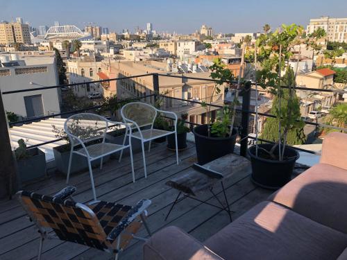 a balcony with chairs and tables and a view of a city at קמפינג על הגג ביפו in Tel Aviv