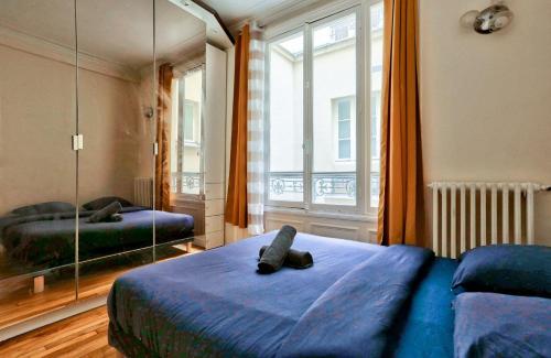 a bedroom with a blue bed and a large mirror at Arc de Triomphe Superbe Appartement Paris in Paris