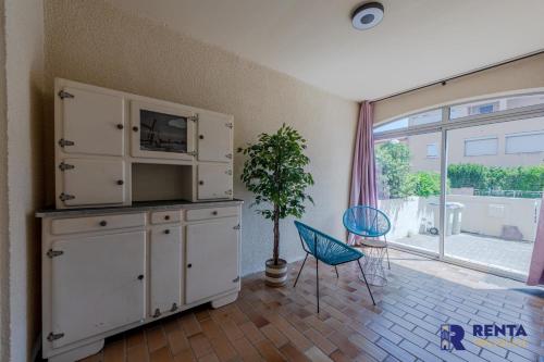 a living room with a tv and a cabinet and a chair at La Perle WIFI Plain Pied Proche Mer in Saint Cyprien Plage