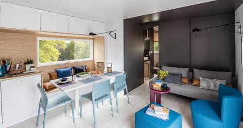 a kitchen and living room with a table and blue chairs at Camping LE PIGEONNIER in Saint-Crépin-et-Carlucet