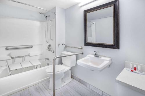 a bathroom with a toilet and a sink and a mirror at Days Inn & Suites by Wyndham Colonial in Williamsburg