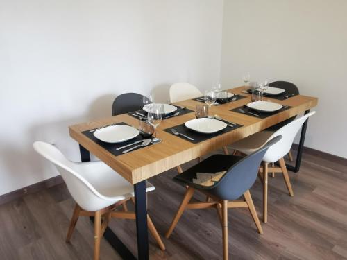 a wooden table with chairs and plates and wine glasses at Appartement Jelyad Mallard proche Disney in Chanteloup-en-Brie