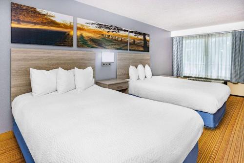 a hotel room with two beds and a painting on the wall at Days Inn & Suites by Wyndham Colonial in Williamsburg