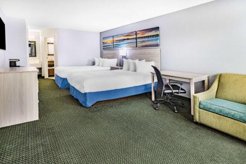 a hotel room with a large bed and a chair at Days Inn & Suites by Wyndham Colonial in Williamsburg