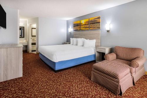 a hotel room with a bed and a chair at Days Inn & Suites by Wyndham Colonial in Williamsburg