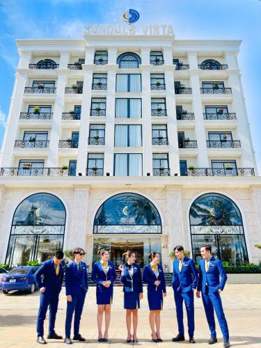a group of people in blue suits standing in front of a hotel at Sandals Vista Hotel in Bao Loc